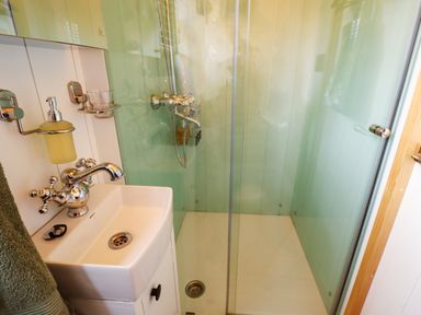 A small bathroom with a white sink and chrome faucet next to a glass shower enclosure at Herdwick Luxury Glamping in Nottingham