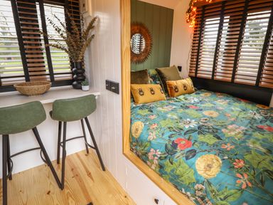 A bedroom with a floral bedspread next to two green chairs at Southdown Luxury Glamping in Nottingham