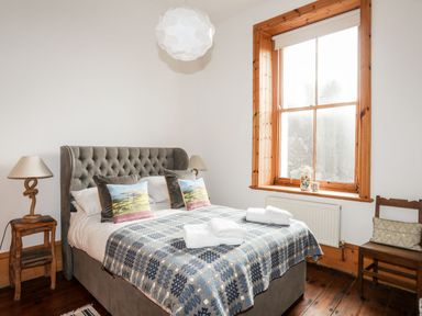 A bedroom with a double bed pillows and folded towels wooden window frame and side tables at East Point Lynas Lighthouse Keeper's Cottage Llaneilian near Amlwch