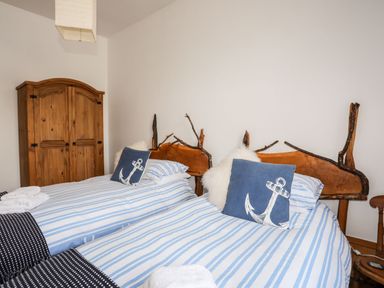 A bedroom with two single beds with wooden headboards and blue striped bedding at East Point Lynas Lighthouse Keeper's Cottage in Llaneilian near Amlwch