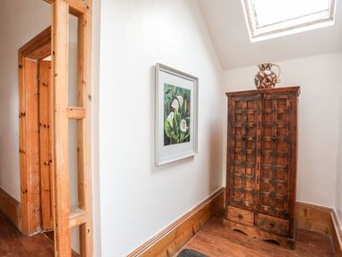 A corner with a wooden cabinet topped with a jug and a framed painting on the wall at East Point Lynas Lighthouse Keeper's Cottage Llaneilian near Amlwch