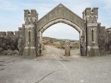 A stone archway with two columns and a road leading through a countryside at West Point Lynas Lighthouse Keeper's Cottage Llaneilian near Amlwch