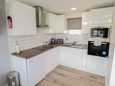 A kitchen with white cabinets and appliances including an oven stove sink and toaster at 39 Cherry Park in Chapel St Leonards