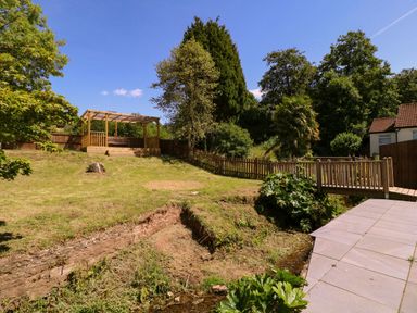 A garden with a wooden deck and a stream at Ranbir House in Longhope
