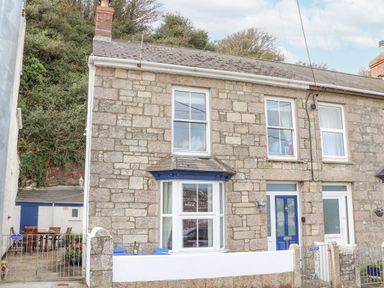 Stone house with bay window blue door and outdoor seating area at Crab Pot Cottage in Porthleven
