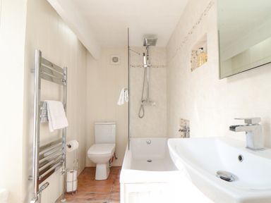 A bathroom with a toilet shower bathtub sink heated towel rail and mirror at Crab Pot Cottage in Porthleven