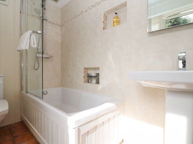 A bathroom with a bathtub shower combination sink and toilet at Crab Pot Cottage in Porthleven