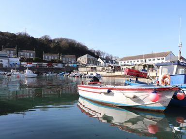 A harbor with boats on water and buildings on the shore at Crab Pot Cottage in Porthleven
