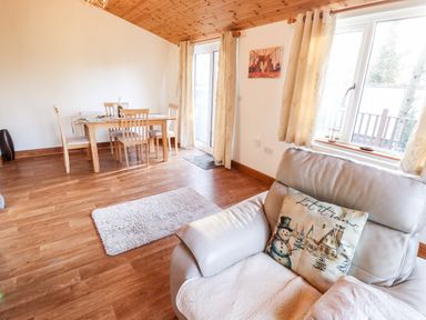 A dining area with a wooden table and chairs and a living area with a sofa and a pillow with a snowman at Kantankye Lodge Thorpe St Peter near Wainfleet All Saints