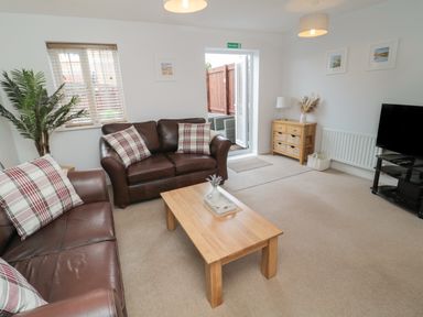 A living room with two brown leather sofas and a wooden coffee table at Brucap Cottage in Beadnell