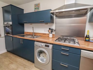 A kitchen with cabinets and appliances at Brucap Cottage Beadnell