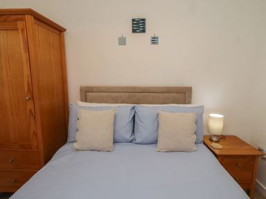 A bedroom with a bed and wardrobe at Brucap Cottage Beadnell