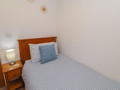 A bedroom with a bed and lamp at Brucap Cottage Beadnell