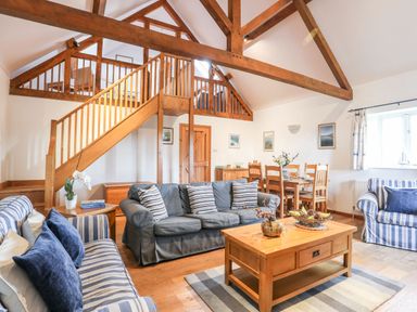 A living room with wooden beams couches and a coffee table at Rhyd Y Bont Bach in Rhoscolyn