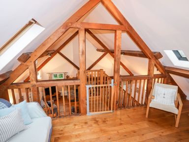 An attic room with wooden beams a wooden floor a small gate two chairs and skylight windows at Rhyd Y Bont Bach in Rhoscolyn