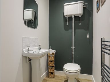 A bathroom with a pedestal sink mirror high level toilet and wicker storage drawers at Iscoed in Llangefni