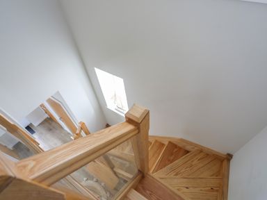 A wooden staircase with glass panels and white walls at Iscoed in Llangefni