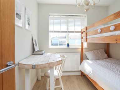 A small bedroom with bunk beds a wooden desk and chair near a window at Iscoed in Llangefni