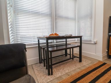 A dining area with a wooden table and benches near windows with white blinds at 11a Manning Road Felixstowe Suffolk
