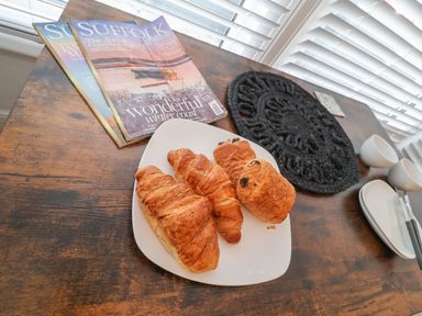 A wooden table with a plate of pastries magazines two white cups and plates at 11a Manning Road Felixstowe Suffolk