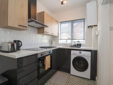 A kitchen with black and wooden cabinets a stove oven washing machine toaster and kettle at 11a Manning Road Felixstowe Suffolk
