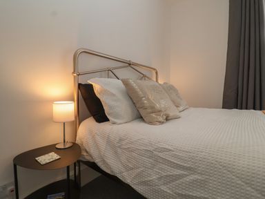 A bedroom with a bed with pillows and a nightstand with a lamp at 11a Manning Road in Felixstowe Suffolk