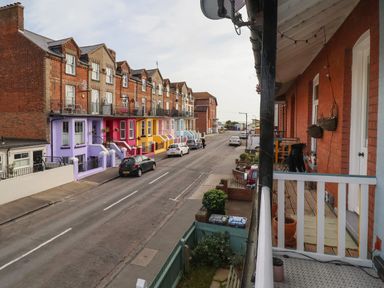 A street with parked cars and multicolored houses viewed from a balcony at 11a Manning Road in Felixstowe Suffolk