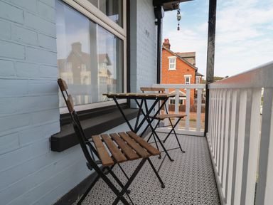 A balcony with two wooden chairs and a small table overlooking houses at 11a Manning Road in Felixstowe Suffolk