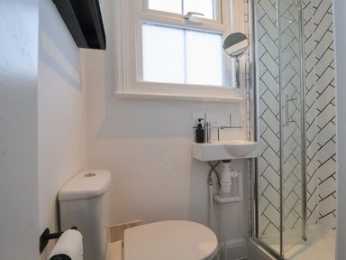 A small bathroom with a toilet sink and a shower with glass doors and tiled walls at 11a Manning Road in Felixstowe Suffolk