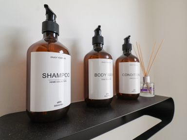 Three brown bottles labeled shampoo body wash and conditioner on a black shelf with a reed diffuser at 11a Manning Road in Felixstowe Suffolk