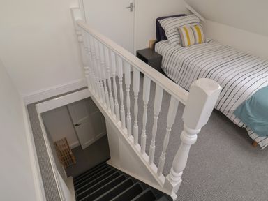A upstairs bedroom with a single bed striped bedding and a bedside table next to a staircase at 11a Manning Road in Felixstowe Suffolk