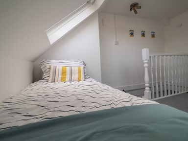 A bedroom with a single bed under a slanted roof window and a white railing at 11a Manning Road in Felixstowe Suffolk