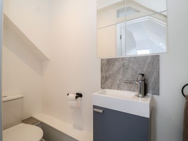 A bathroom with a toilet a sink with a faucet and a mirror at 11a Manning Road in Felixstowe Suffolk