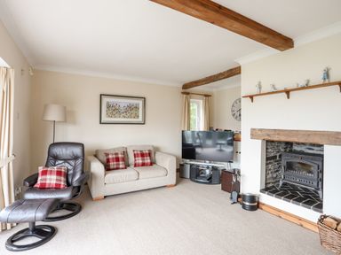 A living room with a sofa and armchair next to a television and fireplace at Bwthyn in Borth-y-Gest near Porthmadog