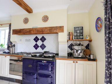 A kitchen with a blue stove white cabinets a coffee machine and decorative plates on the wall at Bwthyn in Borth-y-Gest near Porthmadog