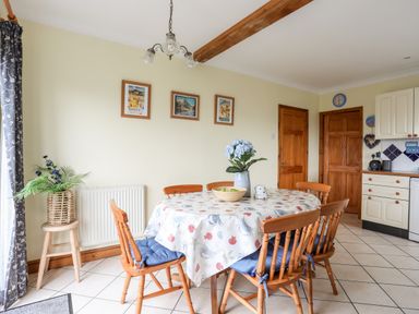 A dining area with a round table and wooden chairs in a kitchen at Bwthyn in Borth-y-Gest near Porthmadog