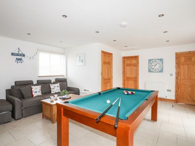 A room with a pool table and a sofa near three wooden doors at Bwthyn in Borth-y-Gest near Porthmadog