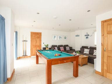 A room with a pool table and two sofas with cushions at Bwthyn in Borth-y-Gest near Porthmadog