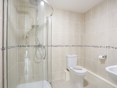 A bathroom with a corner shower enclosure and a toilet with a towel on it at Bwthyn in Borth-y-Gest near Porthmadog
