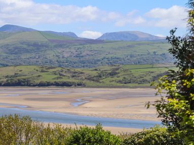 A landscape with a sandy estuary river and green hills in the background at Bwthyn in Borth-y-Gest near Porthmadog