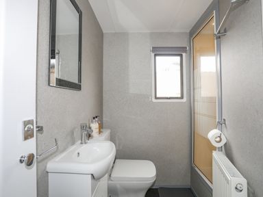 A bathroom with a sink toilet mirror and window next to a shower at Rhiwlas Bach in Benllech