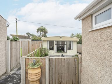 A small yard with a wooden gate and a cream-colored mobile home at Rhiwlas Bach in Benllech