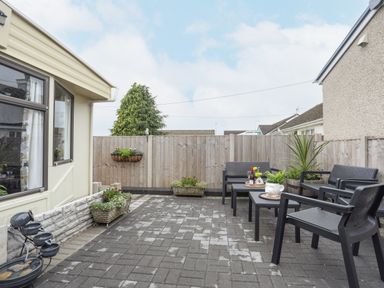 An outdoor patio with black chairs and tables surrounded by planters and a wooden fence at Rhiwlas Bach in Benllech