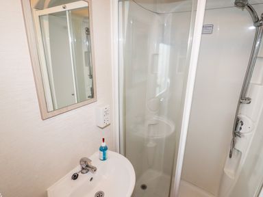 A bathroom with a sink a mirror and a shower enclosure at Beachcomber D35 in Towyn