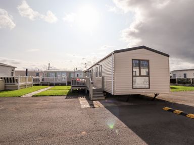 A mobile home with stairs on a paved area surrounded by grass at Beachcomber D35 in Towyn