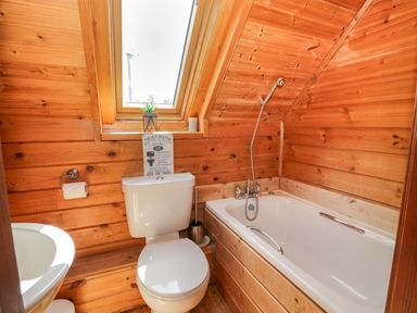 A bathroom with a toilet a bathtub a sink and a skylight window at Glenisle in Dalbeattie