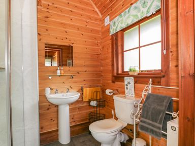 A bathroom with wooden walls a pedestal sink a toilet a window and towels at Glenisle in Dalbeattie