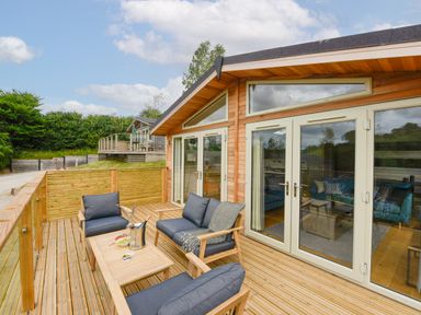 An outdoor wooden deck with seating and a table at 4 Valley View in Lanreath
