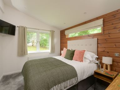 A bedroom with a bed and bedside table with books and lamp at 4 Valley View in Lanreath