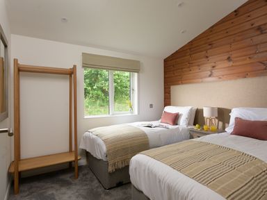 A bedroom with two single beds bedside table and wooden clothing rack at 4 Valley View in Lanreath